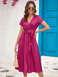 Detail of burgundy polka dot wrap dress featuring a deep V-neck and waist tie design
