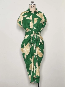 Detail of green leaf print dress with button-down collar and waist tie on a mannequin