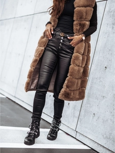 Détail d'un long gilet en fausse fourrure marron avec pantalon en cuir noir et bottines cloutées