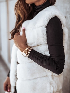 Gros plan sur la texture du gilet en fausse fourrure blanche avec un col roulé noir