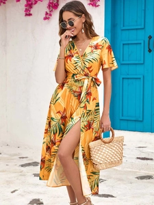 Detail of summer yellow floral wrap dress with high slit and tropical leaf print pattern