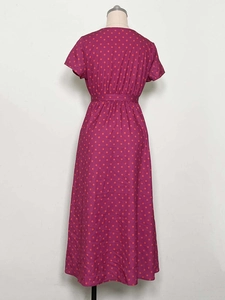 Back view of a dark pink short sleeve midi dress with orange polka dots and waist belt