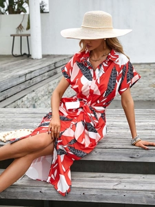 Detail of red tropical leaf print shirt dress with button-front and waist tie belt