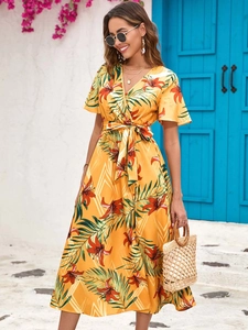 Detail of yellow tropical floral midi dress with V-neckline and ruffle sleeves on beach vacation