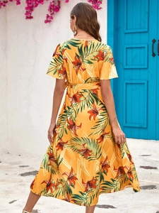 Detailed back view of a yellow floral maxi dress with tropical lily prints and waist tie