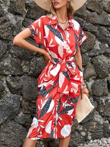 Detail of red tropical print shirt dress featuring a waist bow and front button closure