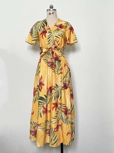 Detail of yellow tropical floral print dress with V-neck and waist tie on mannequin