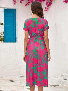 Back view of a summer V-neck floral midi dress with a waist belt in a resort setting