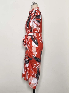 Side view of red short sleeve dress featuring black and white leaf prints and waist tie