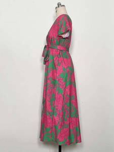 Detail of floral V-neck maxi dress featuring bright pink flowers on a green background