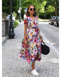 Detail view of floral print wrap dress with V-neck and front slit on a cobblestone street