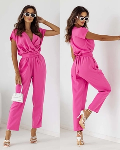 Detail of bright pink V-neck jumpsuit with waist tie and short sleeves on model
