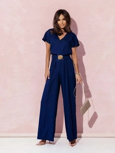 Détail de la combinaison bleu foncé à col en V avec ceinture à boucle dorée et jambes larges