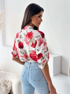 Detail view of red floral print shirt with sleeve button tabs and blue high waist jeans