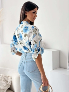 Detail view of white shirt with blue floral patterns and roll-up sleeves in a side pose