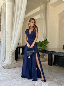 Navy blue evening gown featuring a deep V-neck, shoulder bows, and an elegant high side slit