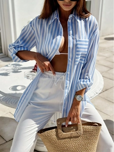 Close-up of blue white striped shirt with white drawstring trousers and woven straw bag