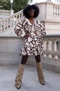 Detail showing the deep V-neck and ruffled hem of a cream abstract floral wrap dress
