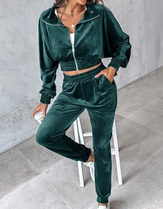 Detail view of dark green velvet tracksuit showing soft glossy fabric and zip-up collar