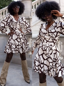 Detail of V-neck long sleeve dress featuring black and white print and ruffled hemline
