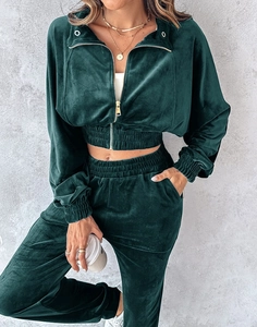 Detail of dark green velvet tracksuit showing golden zipper and elastic ribbed cuffs