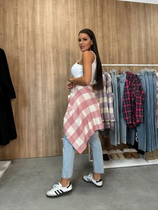 Street style view of a pink plaid shirt tied around the waist with blue denim jeans
