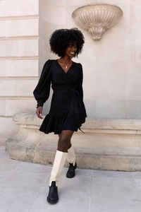 Detail of elegant black wrap dress featuring a V-neckline and ruffled hemline in a street setting