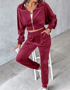 Detail of burgundy velvet tracksuit showing high waist joggers and cropped zip-up jacket