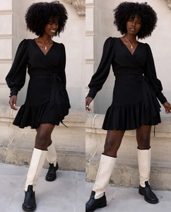 Detail of V-neck printed mini dress featuring ruffle hem and lantern sleeves with waist tie
