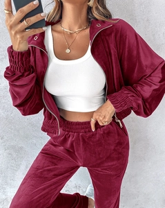 Detailed texture of burgundy velvet tracksuit featuring a zip-up jacket and matching pants