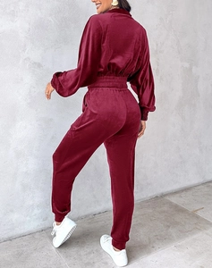 Detail of burgundy velvet tracksuit with elasticated cuffs and high-waist joggers texture