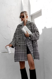 Gros plan d'un manteau pied-de-poule noir et blanc avec grand revers et double boutonnage