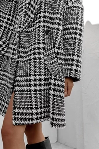 Détail du manteau en laine épais à motif pied-de-poule noir et blanc avec bouton