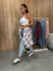 Detail of a purple plaid shirt tied around the waist with casual denim outfit in a boutique