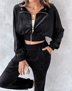 Detail of black velvet tracksuit set featuring gold zipper and soft velvet texture