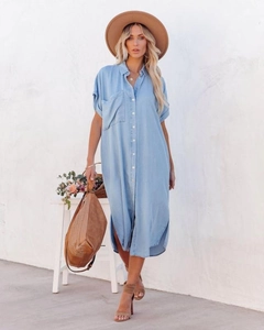 Detail of light blue denim midi shirt dress featuring button closure and side slits