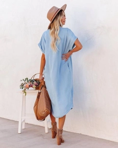 Detail of light blue denim midi dress featuring side slits and curved hemline design