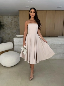 Detail of light apricot strapless midi dress featuring pleated waist and flowy skirt