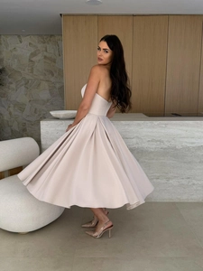 Detailed view of champagne satin midi dress featuring elegant pleated hem and smooth texture
