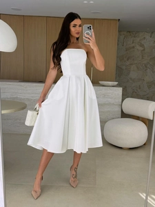 Detailed view of a white strapless A-line midi dress with pleated texture and fitted waist