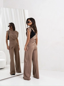 Detail of tan sleeveless jumpsuit featuring cross-wrap waist and wide-leg trousers