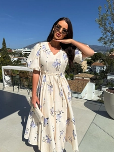 Detail of a floral V-neck midi dress with puff sleeves and waist tie in a resort setting