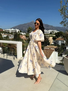 Detail of V-neck floral maxi dress with puff sleeves and tie-waist in a resort setting