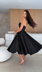 Detail of elegant black strapless midi dress with a voluminous flared A-line skirt