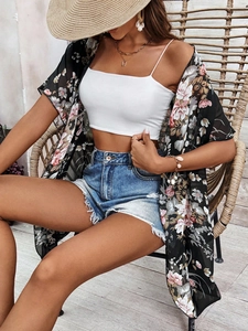 Detail of floral chiffon cover up styled with denim shorts and seashell accessories