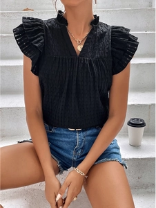 Detail of black V-neck top with ruffle sleeves and textured fabric on casual denim shorts