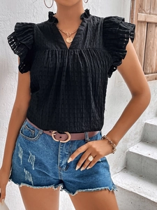Detail of black V-neck ruffled top with textured fabric and delicate pleated sleeves
