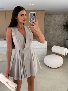 Détail de la robe sans manches croisée gris clair avec boutons dorés et col en V