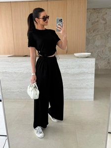 Detail eines schwarzen Zweiteilers mit Crop-Top mit Kordelzug und Hose mit weitem Bein