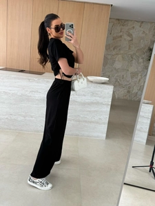 Detail eines schwarzen Zweiteilers mit Crop-Top mit Kordelzug und weit geschnittener Hose